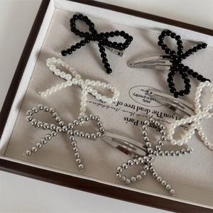 Close-up of handmade beaded bow hair clips in black, pearl white and silver finish
