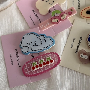 Close-up of cute cartoon puppy hair clips on pink display cards with acrylic charms
