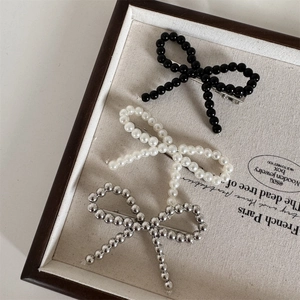 Detailed close-up of a three-piece bow hair clip set in pearl, black, and silver beads