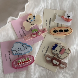 Close-up of cute cartoon puppy hairpins and cherry clips on a cream display card