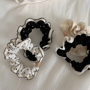 Close-up of polka dot scrunchies with lace edges and wooden beads on white fabric