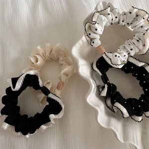 Detailed view of polka dot and lace chiffon scrunchies set on elegant ceramic plate