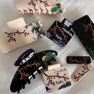 Detailed close-up of acetate hair claws with Chinese plum blossom and bamboo ink patterns