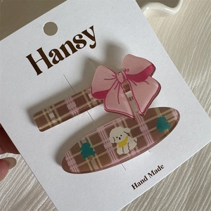Primer plano de clips para el pelo a cuadros con lazo rosa y diseño de cachorrito