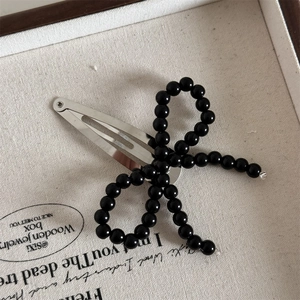 Detail view of a black beaded bow hair clip on a vintage decorative display tray