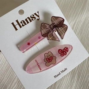 Detalle de pinza para el pelo con lazo rosa y horquilla de oso en tarjeta