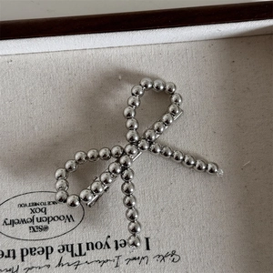 Close-up of a silver beaded bow hair clip showing metallic texture and pearl finish