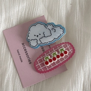 Close-up of cute cartoon puppy cloud and pink cherry hair clips on soft fabric background