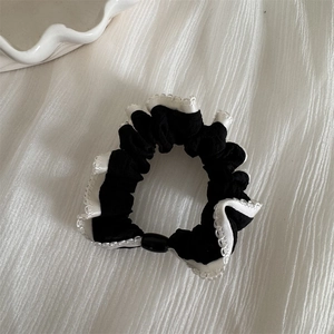 Detail of black scrunchie with white lace edges and elegant oval buckle fastener