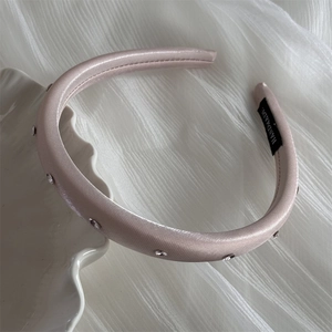 Vue détaillée du serre-tête en satin rose champagne avec de fins strass argentés