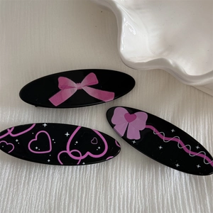 Set of three black oval hair clips with pink bow and heart patterns for girls