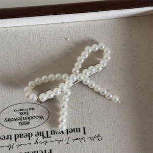 Detail of beaded pearl bow hair clip with silver metal alligator base on canvas