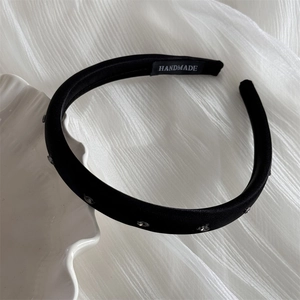 Détail d'un serre-tête fait main en satin noir avec strass décoratifs sur fond blanc