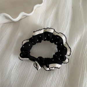 Macro shot of a black and white polka dot scrunchie with delicate lace trim detailing