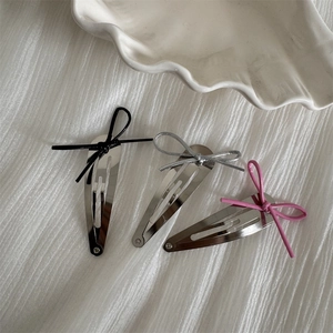 Close-up of metallic teardrop hair clips with black silver and pink string bows