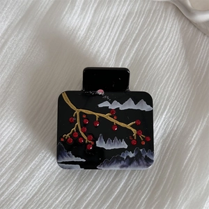 Detail of acetate shark clip featuring traditional plum blossom and mountain scenery