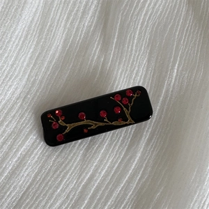 Detail showing red rhinestone plum blossoms on a black acetate hair claw clip