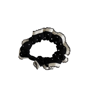 Polka dot hair scrunchie in black with white ruffle edge for elegant ponytail styling