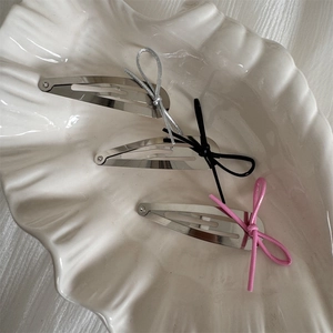 Silver teardrop metal hair clips with grey black and pink ribbon bows in a white shell tray