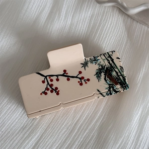 Detailed macro of acetate hair claw with red plum blossom and black ink bamboo patterns