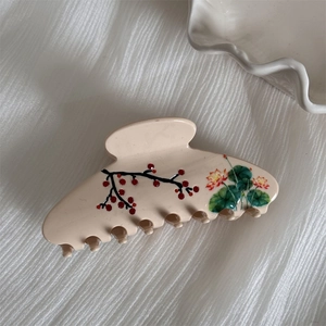 Close-up of acetic acid hair claw with elegant red plum blossom and green leaf pattern