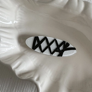 Detailed view of white acrylic hair clip with black ribbon bow and corset style lacing