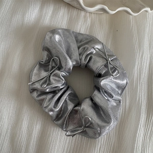 Detail of silver metallic scrunchie with three string bows and laser glitter texture