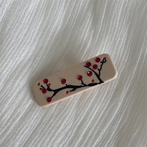 Detail of a rectangular hair claw with plum blossom patterns and colorful rhinestones