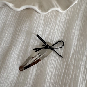 Close-up of minimalist silver metallic hair clip with a delicate black bow decoration