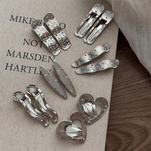 Close-up of geometric silver metal hairpins with colorful 3D dots on vintage canvas book
