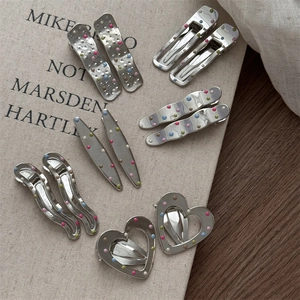 Detail of silver metal hair clips with colorful polka dots in various shapes and styles