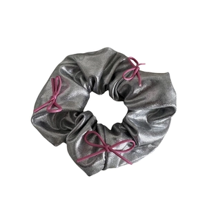 Silver metallic scrunchie featuring pink faux leather bows for a stylish aesthetic