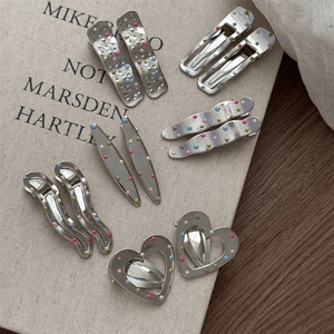 Detailed close-up of various silver metal hair clips with colorful polka dots and cute shapes