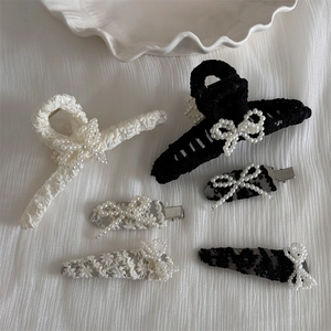Detailed close-up of lace hair clips with pearl bow accents in black and white colors