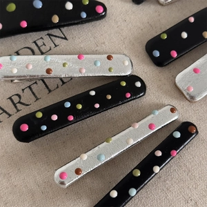 Detail shot of colorful polka dot hair clips with polished enamel finish on linen background