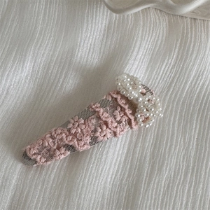 Detailed view of pink lace bow hair clip with white pearls and elegant embroidery