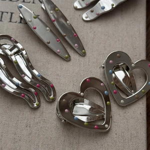 Detail of silver metal hair clips with colorful polka dots in heart and wave shapes