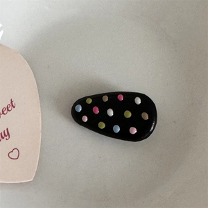 Detail shot of black BB hair clip with colorful polka dots on gray background
