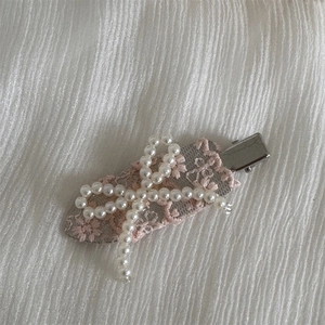 Detail of lace hair clip with pearl bow and pink floral embroidery on metal duckbill base