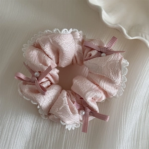 Detailaufnahme von rosa Jacquard-Haargummi mit weißer Spitze und Perlen-Schleife