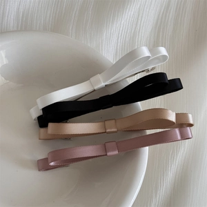 Détail de quatre barrettes à cheveux double nœud en noir, blanc, doré et rose poudré