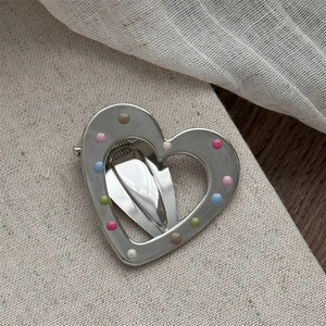 Detail of silver heart hair clip with colorful dots and duckbill clamp mechanism