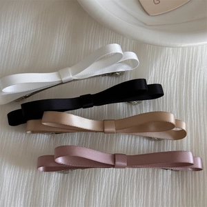 Détail de barrettes à nœuds en ruban de satin élégant en noir, blanc, or et rose
