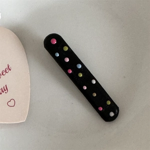 Close-up of black rectangular hair clip with colorful matte polka dot pattern detail