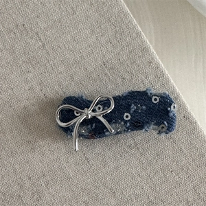 Macro view of blue denim hair clip with silver metal bow and shiny sequins detail