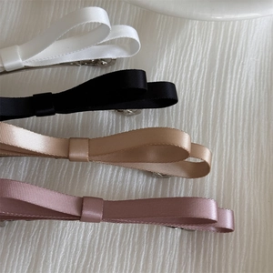 Détail de barrettes à double nœud en ruban en blanc, noir, beige et rose poudré
