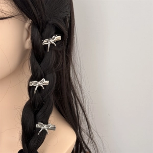Trois barrettes à cheveux nœud argenté à finition métallique sur une tresse noire