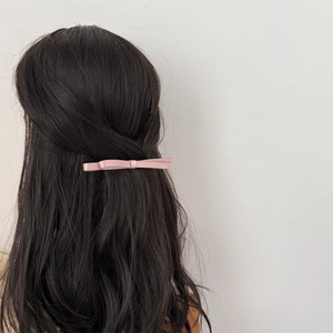 Barrette à cheveux à double nœud rose sur un modèle aux longs cheveux bruns