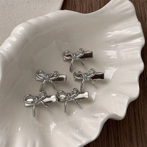 Lot de 5 barrettes nœuds argentées sur une assiette coquillage avec une table en bois