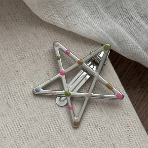 Close-up of star-shaped silver metal hair clip with colorful enamel polka dots detail